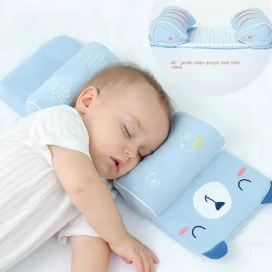 Baby sleeping on a blue pillow with cartoon designs on a white background